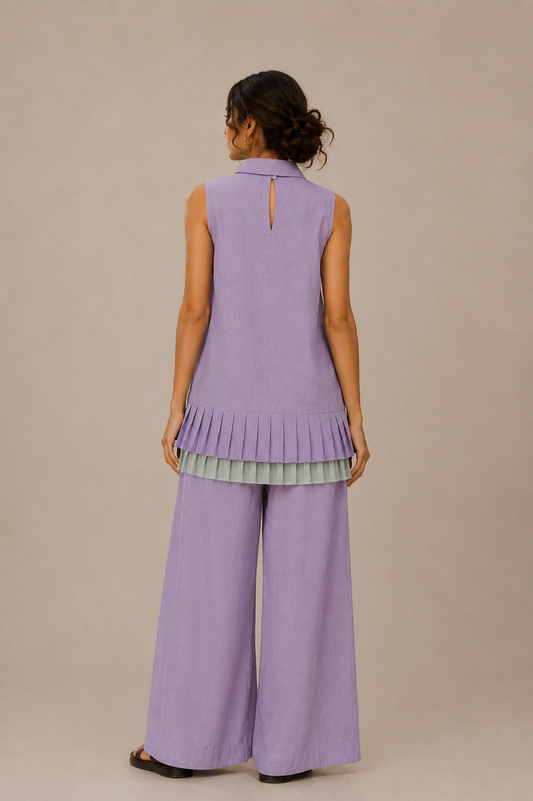 A woman shown from the back wearing a lavender sleeveless top with a pleated hem and matching wide-leg pants from Cords Theory